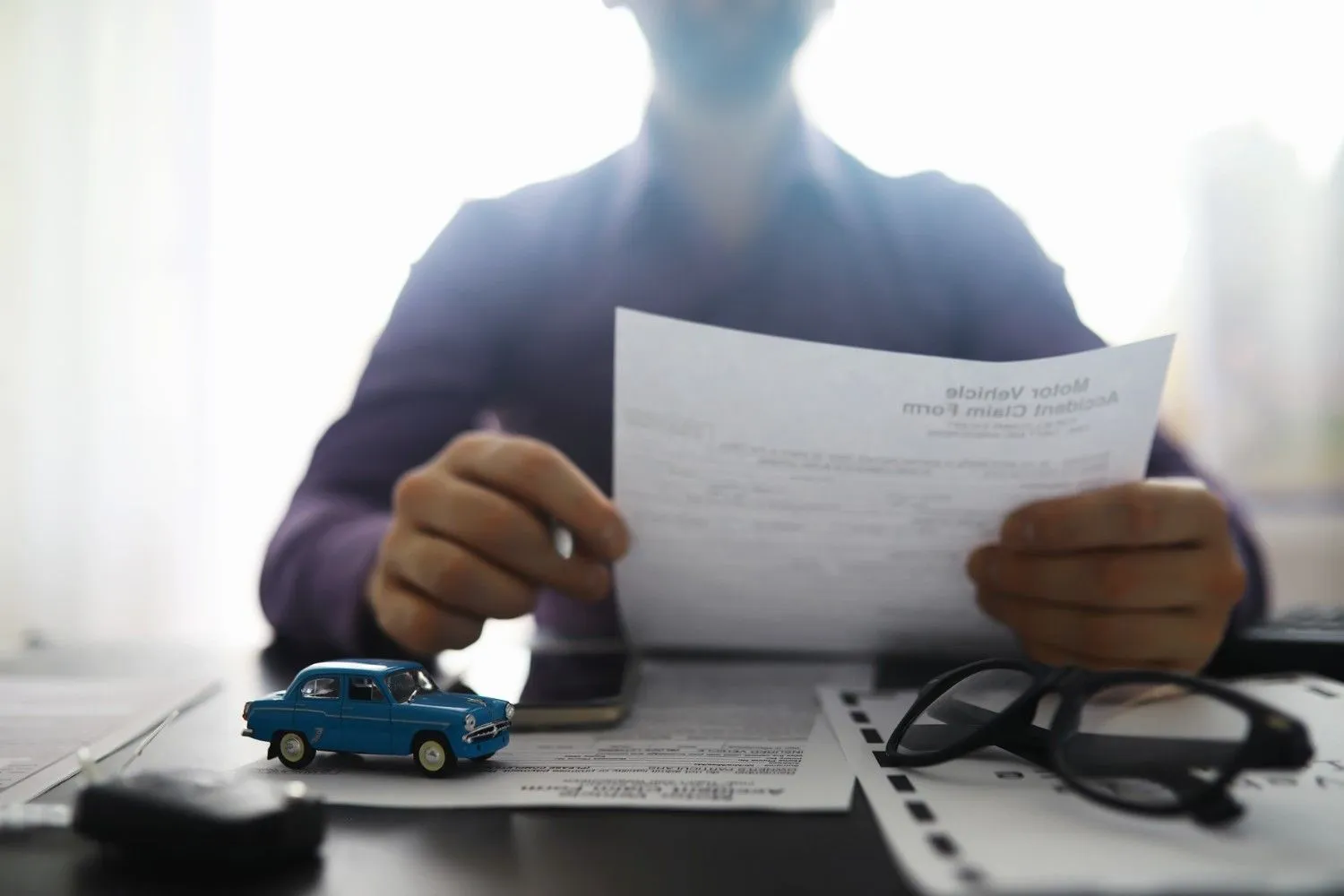Car keys and insurance paperwork on a desk